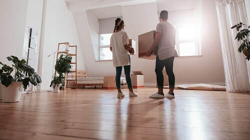 Deux personnes déplaçant des cartons dans un appartement vide, prêt pour un déménagement, ambiance lumineuse. préparation déménagement checklist intégré naturellement.