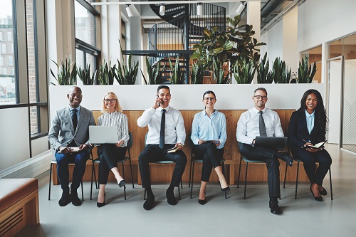 Groupe de professionnels assis en rangée dans un espace moderne, certains avec des ordinateurs, prêt pour un rendez-vous d’affaires. [choses à ne pas oublier pour un déménagement]